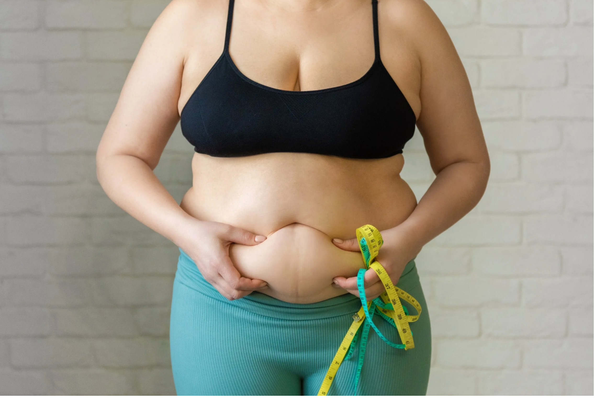 Woman holding belly fat with a measuring tape - Cortisol and weight gain